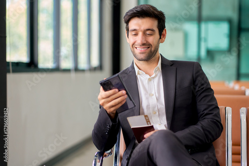 Businessman in black suit sitting on waiting area for check in to travel.