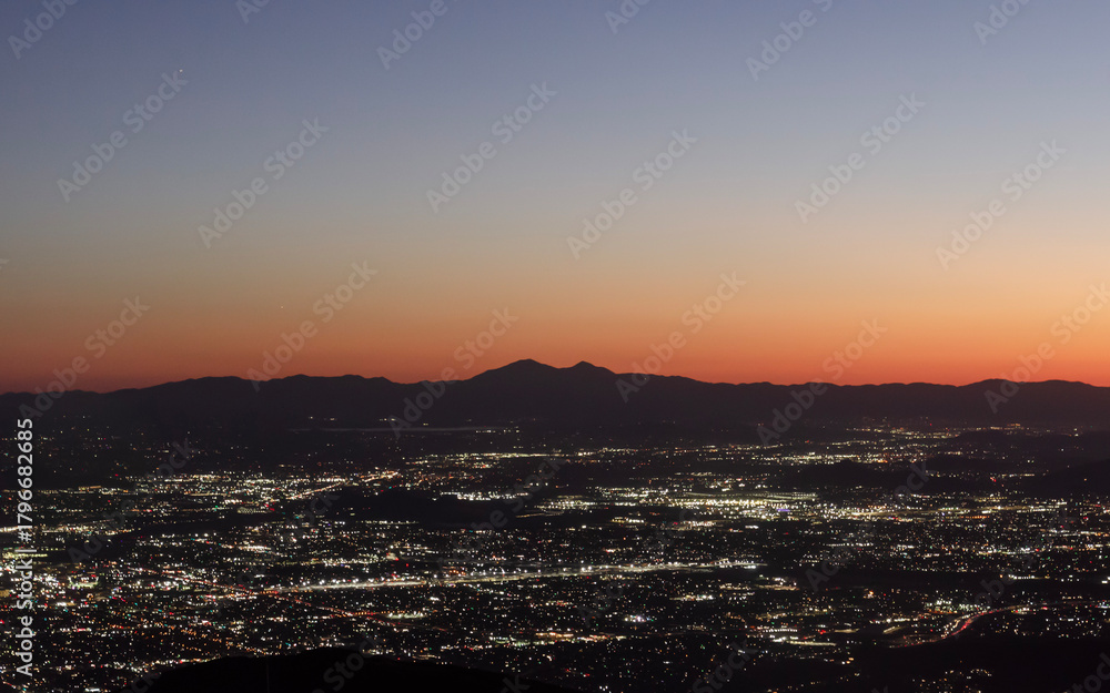 Fototapeta premium sunset mountain silhouette at dawn with city light