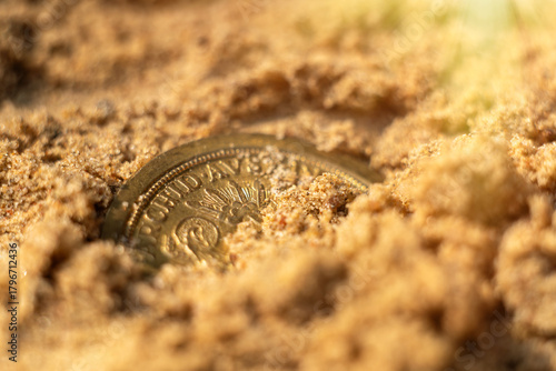 A gold coin in the sand on the beach.Find a treasure trove of coins.Jewelry search.