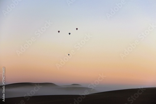 Morning view from camp, while having a freshly brewed coffee. Dubai hot air balloon ride in the distance while the mist rolls over the desert landscape.