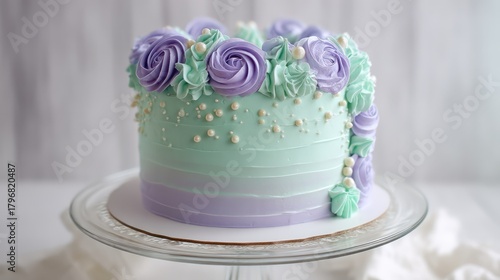 Pastel mint-green cake with ombre lavender accents decorated with buttercream roses and fondant pearls. Cake displayed on a
