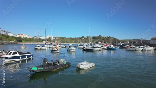 Boats moored in Tenby harbour at high tide on a bright sunny day.