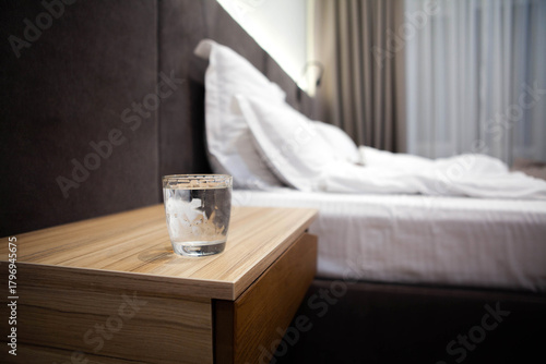 Glass of water on a bedside table in a cozy bedroom, symbolizing hydration, wellness, and post-workout recovery in a calm self-care setting.