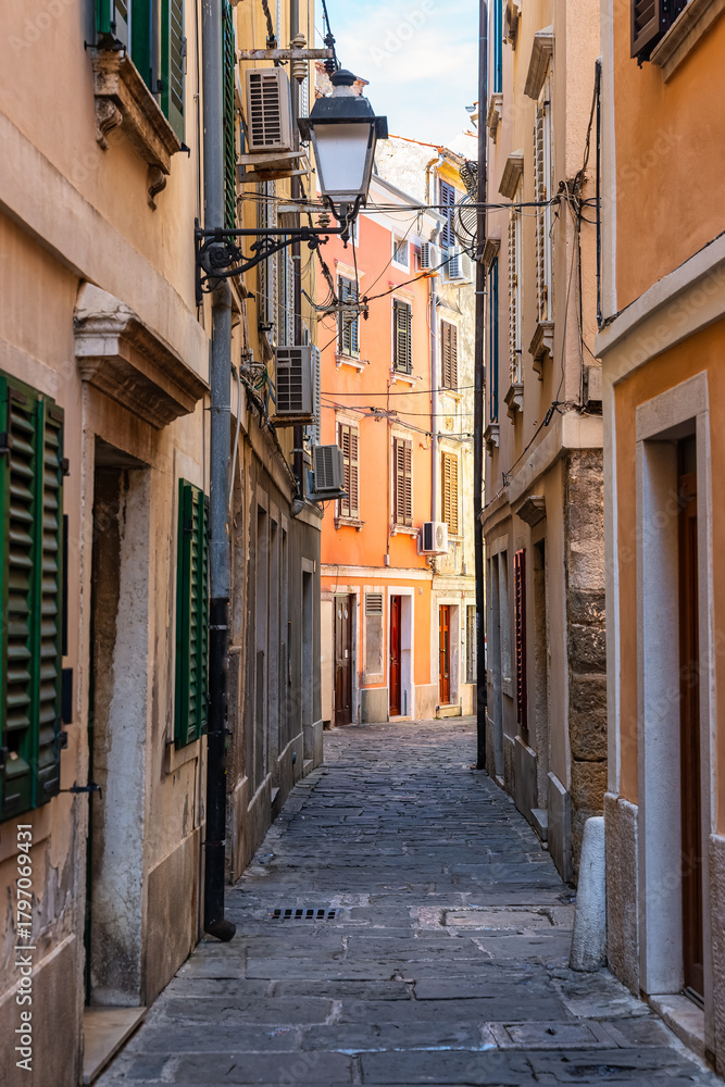 Fototapeta premium Picturesque street with cobbled floor and colorful old houses in the coastal town of Piran, Slovenia.
