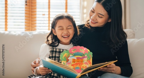 Joyful moments between mother and daughter while reading a pop-up book at home in the afternoon light
