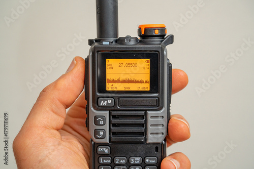 Walkie-talkie quanshueng uv5 radio with frequency display, held in hand.
