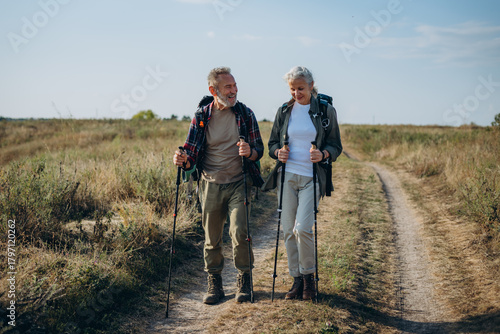 Active pensioners friends exercise Nordic walking in fall farmland