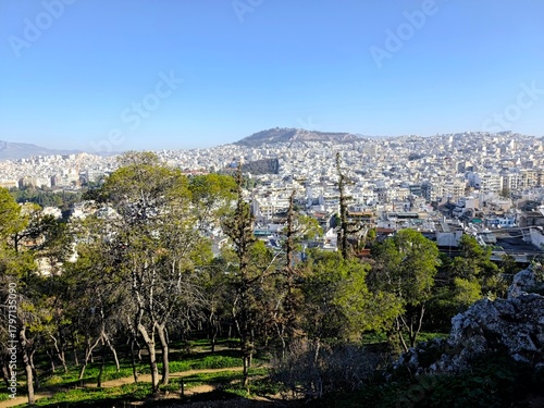 Fototapeta Naklejka Na Ścianę i Meble -  Panoramic view of Athens, Greece, unfolding beneath a vivid blue sky, captured from the summit of Strefi Hill in the heart of Exarcheia neighborhood.