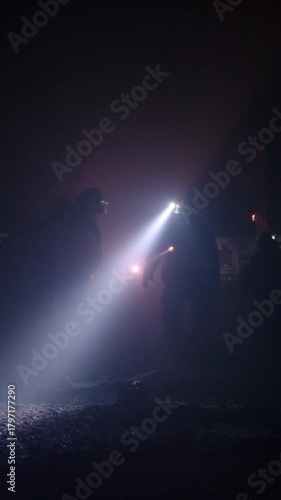 Rescue forces search for survivors inside a dark tunnel using flashlights