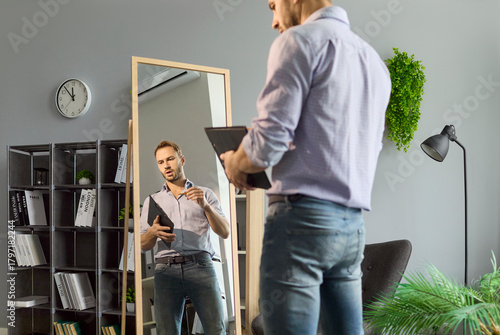 Fototapeta Man job seeker rehearses interview speech before office mirror