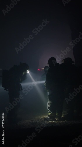 Rescue forces search for survivors inside a dark tunnel using flashlights
