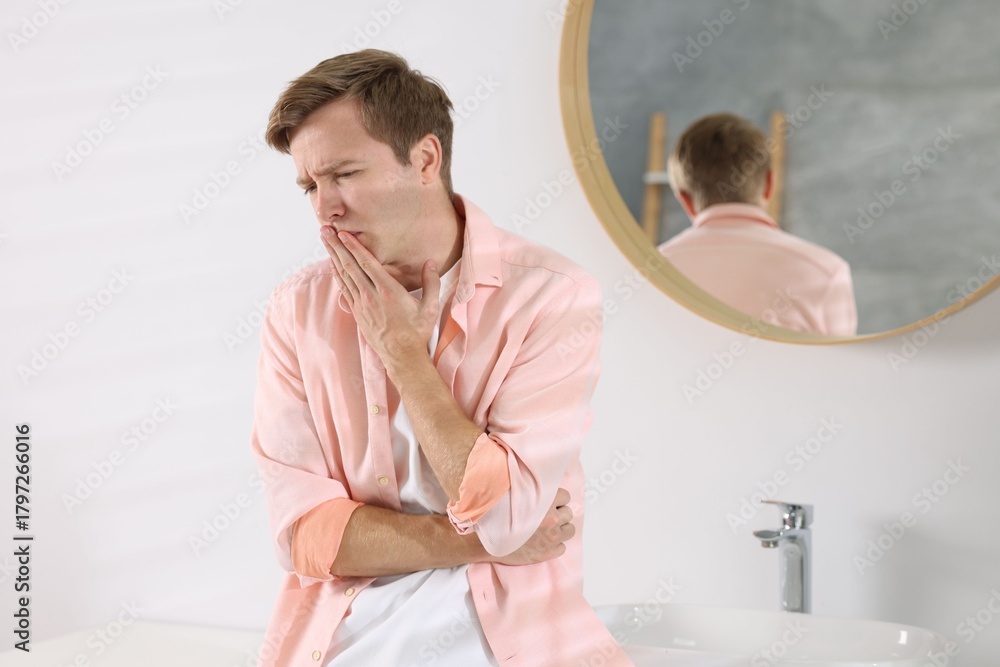 Fototapeta premium Young man suffering from nausea and stomachache in bathroom