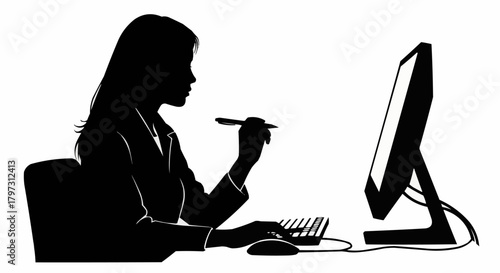 Silhouette of a professional woman working at her computer desk.