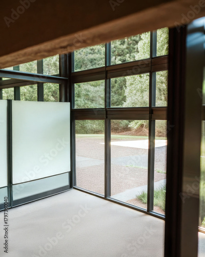 Modern empty room with large glass windows and frosted glass panel, natural light creating calm and peaceful atmosphere
