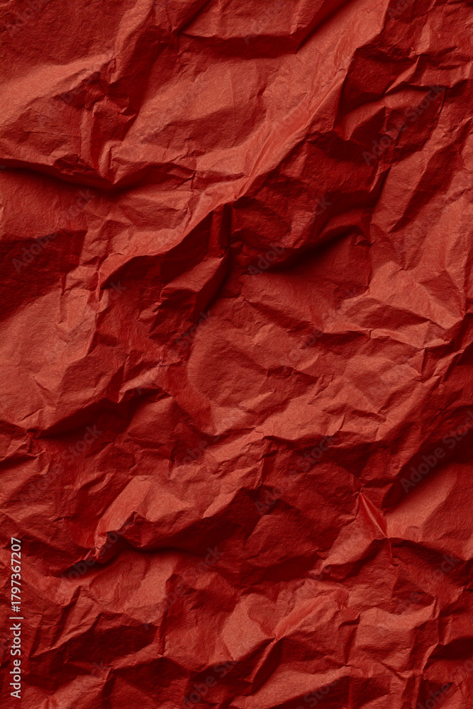Fototapeta premium Close up textured background of crumpled red paper with deep shadows and highlights