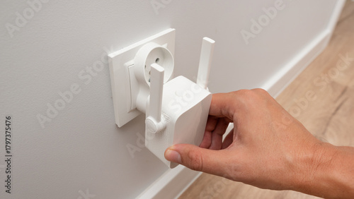 Wireless Wi-Fi repeater on white wall indoors