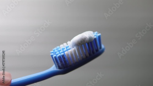 Applying toothpaste to a blue toothbrush. Health theme. Hygiene theme.