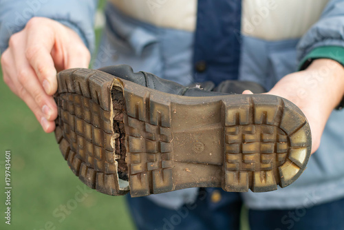 Torn Boot. A man holds an old boot in his hands.