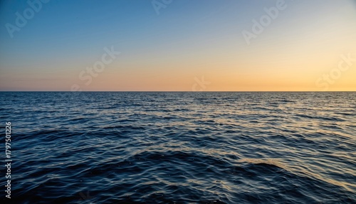 Fototapeta Naklejka Na Ścianę i Meble -  Vast Ocean Surface Under a Warm Sunset Sky with Gentle Waves and Calm Horizon During Golden Hour
