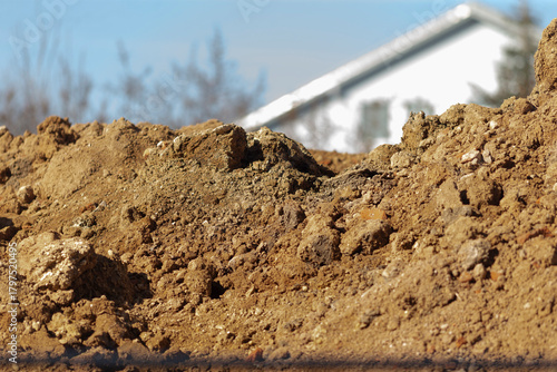 excavated soil near house with landscaping details, sunlit yard showing foundation prep and soil backfill, closeup of loose excavated soil in front yard during foundation work and landscaping