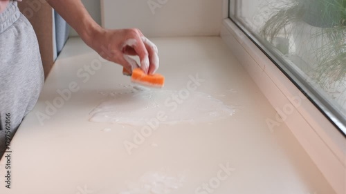 A man washes a windowsill with a foamy sponge close-up of hands