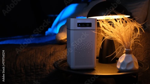 Air purifier operating standing on a bedside table in the evening