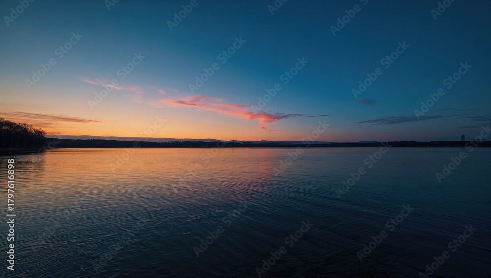 Obraz premium Sunset over a lake shoreline, emphasizing natural beauty and serenity