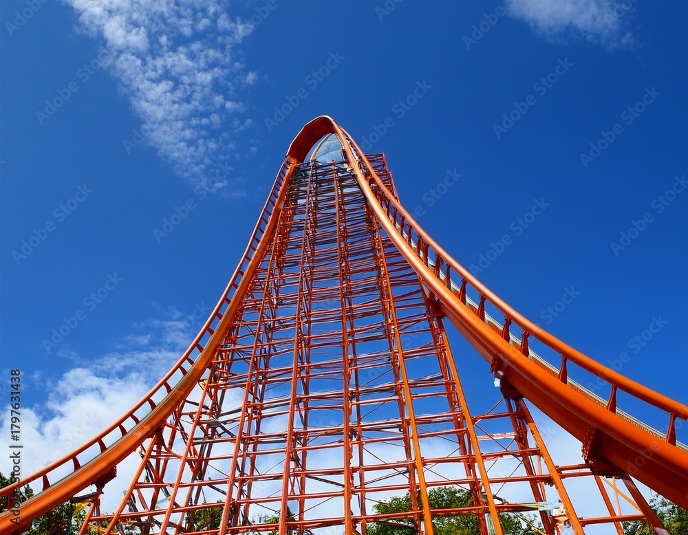 Obraz premium orange rollercoaster track against a bright blue sky curving and reaching upward promising thrill and adventure