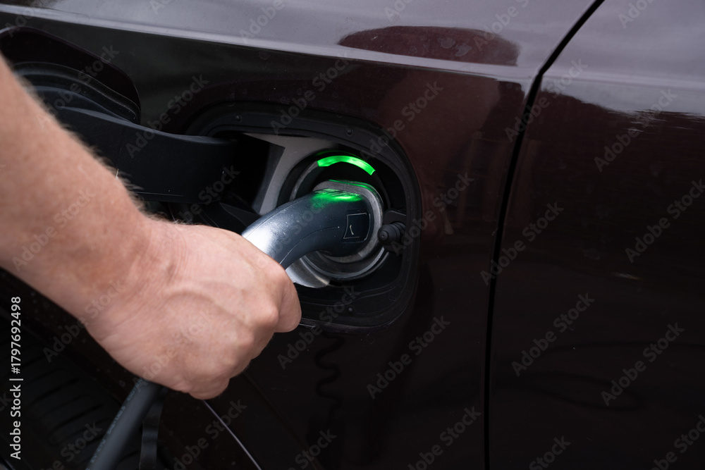 Fototapeta premium Close-up of male hands connecting an electric charger in a car.