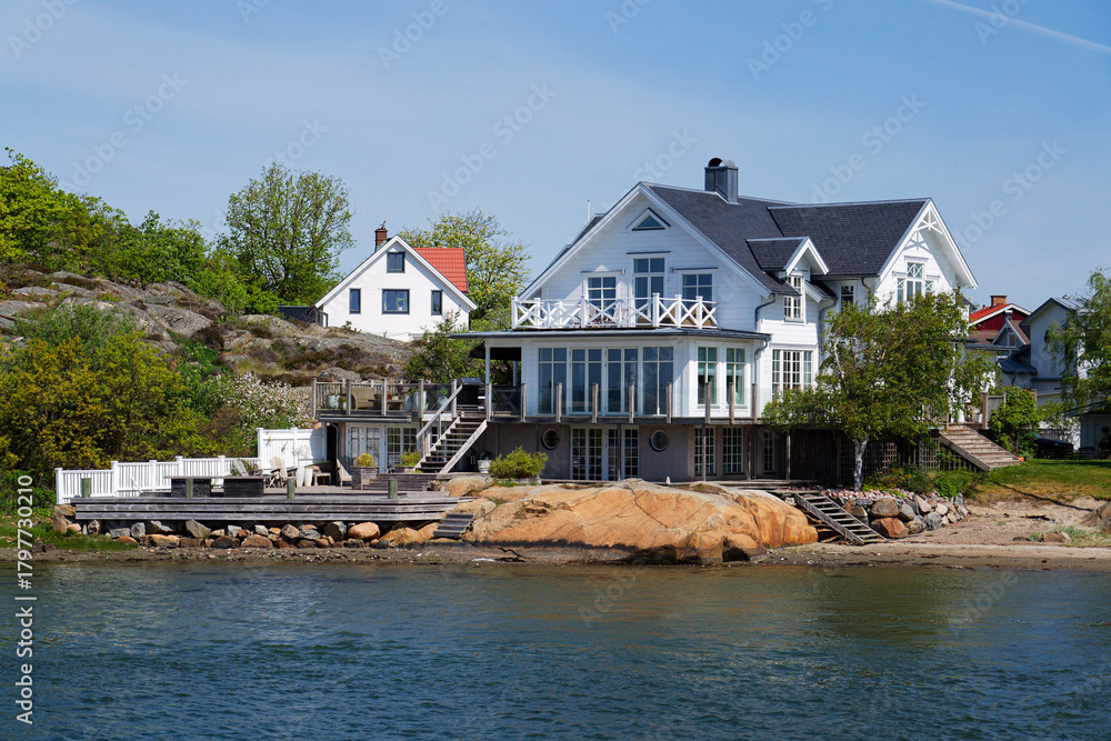 Obraz premium Houses on the rocks of Saltholmen peninsula on shore of Alvsborgsfjorden harbour, Alvsborg district, sunny day, Gothenburg, Sweden
