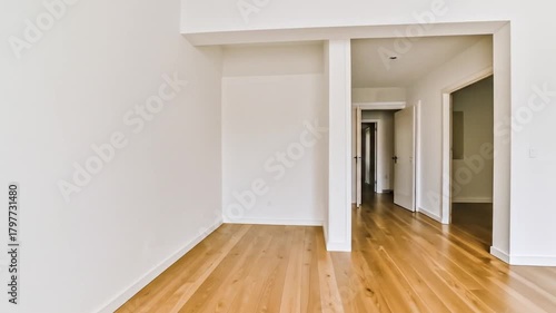 Interior shot of a modern apartment with wood flooring and white walls, leading to a hallway