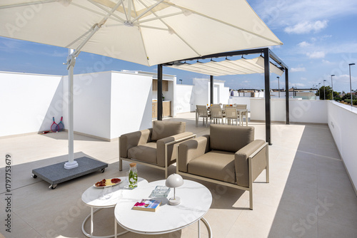 Fotografie Sunny rooftop terrace with seating area and umbrella