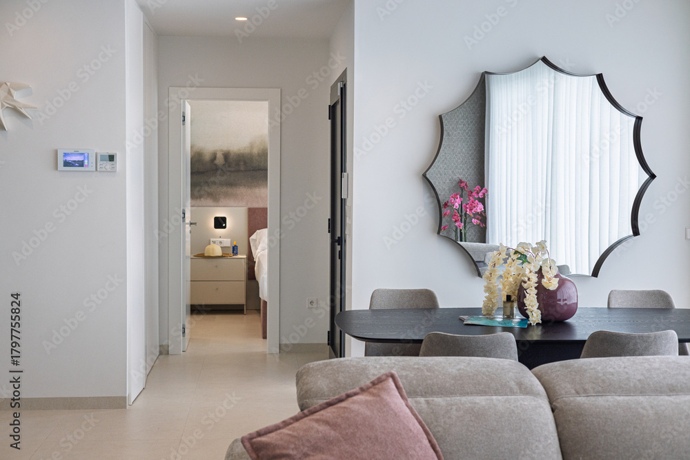 Fototapeta premium Cozy modern living space with mirror, dining table and view into bedroom interior