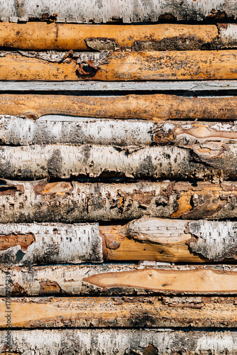Stacked birch logs with natural bark texture, horizontal arrangement reveals alternating light and dark wood tones, subtle cracks and rough surfaces add authenticity. Rustic cabin concept