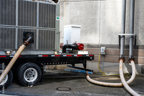 temporary pumping system mounted on trailer set up outside a building, likely for fluid transfer or a bypass operation