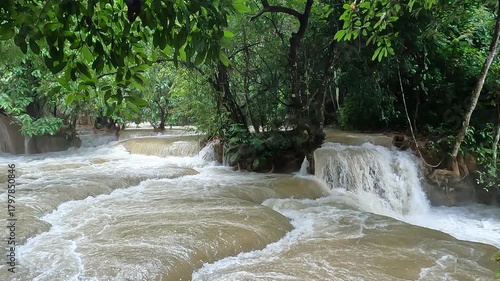 Powerful water flow at the large waterfalls near Luang Prabang, Laos, filmed on a cloudy, winter-like day, capturing the dramatic natural beauty of the scene.