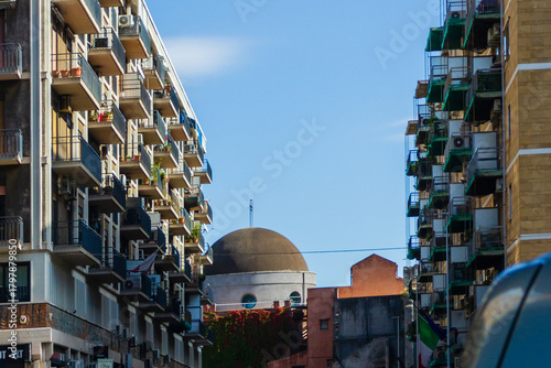 Urban Cityscape With Stacked Apartments And Dome-Shaped Building Under Clear Blue Sky