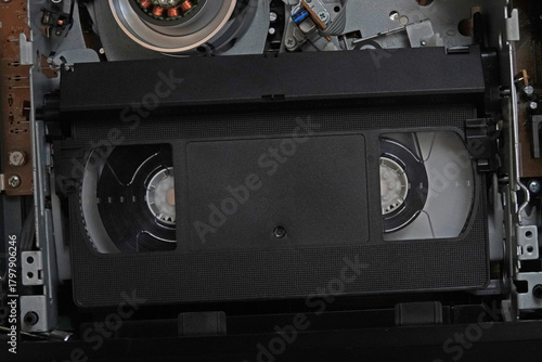 An unlabeled, vintage VHS tape is shown in a VCR machine unit up close.