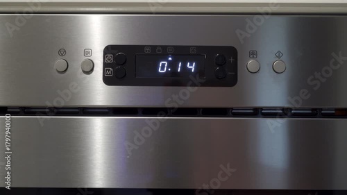 Stainless steel microwave control panel with digital display showing the time countdown. The timer reaches zero. A sharp, loud, continuous electronic beeping sound signals the end of the cooking cycle