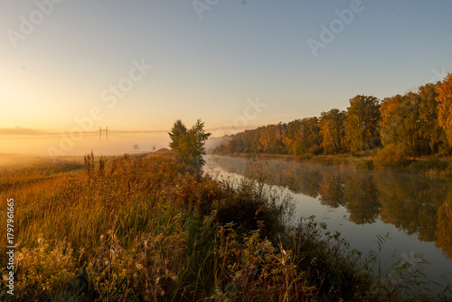 Morning fog over the lake at dawn. The surrounding trees are reflected in the calm water, creating an atmospheric landscape.
