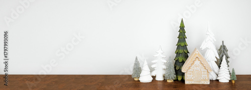 Green and white Christmas tree and gingerbread house decor on a wood shelf against a white wall banner background with copy space