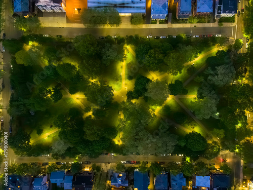 The warm light of dusk illuminates the geometric paths and green trees of Wooster Square Park in New Haven, CT, USA.
