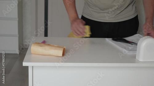 A man wipes a white table, a cleaner disinfects and wipes the table with a rag