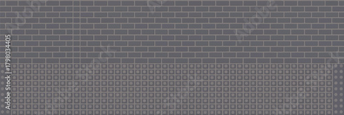 A gray brick wall with a section of smaller square tiles below it creating a textured background