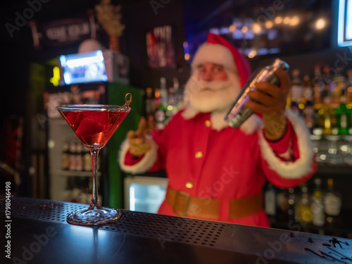 Santa Claus works at the bar making cocktails in a shaker. 