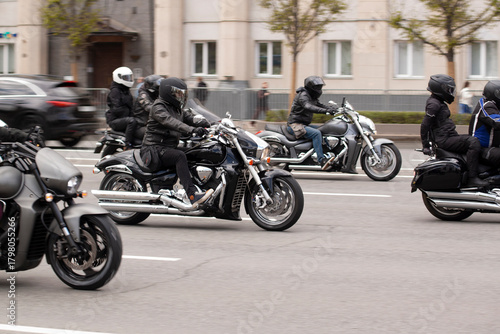 group of motorcyclists rides through a summer city