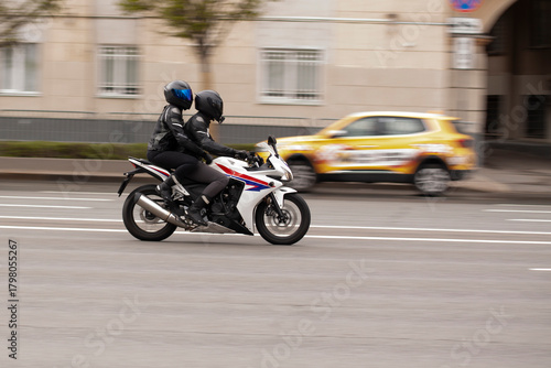 Two people are riding a motorcycle through a summer city