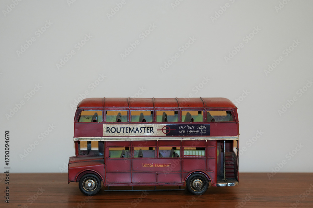 Fototapeta premium Bucharest Romania 16 November 2025.A vintage painting of a classic red English bus displayed on a wooden table. The artwork features the iconic double-decker bus in retro tones.