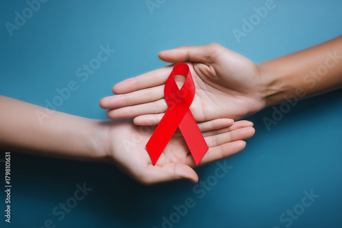 Ruban rouge symbole du Sidaction transmis de main en main sur fond bleu avec espace négatif copyspace visuel de sensibilisation lutte contre le sida Journée mondiale 1er décembre