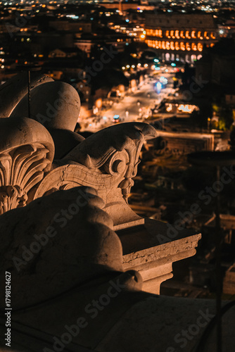 Fototapeta Naklejka Na Ścianę i Meble -  Extreme close-up of a stone sculpture detail at night, overlooking a street and the illuminated city lights in the blurred background.